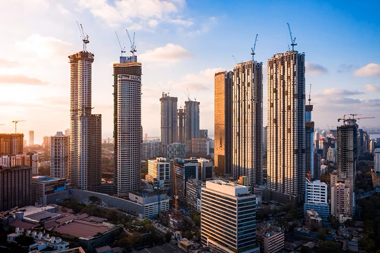 Tall skyscrapers under construction with cranes, set against a sunrise skyline with scattered clouds