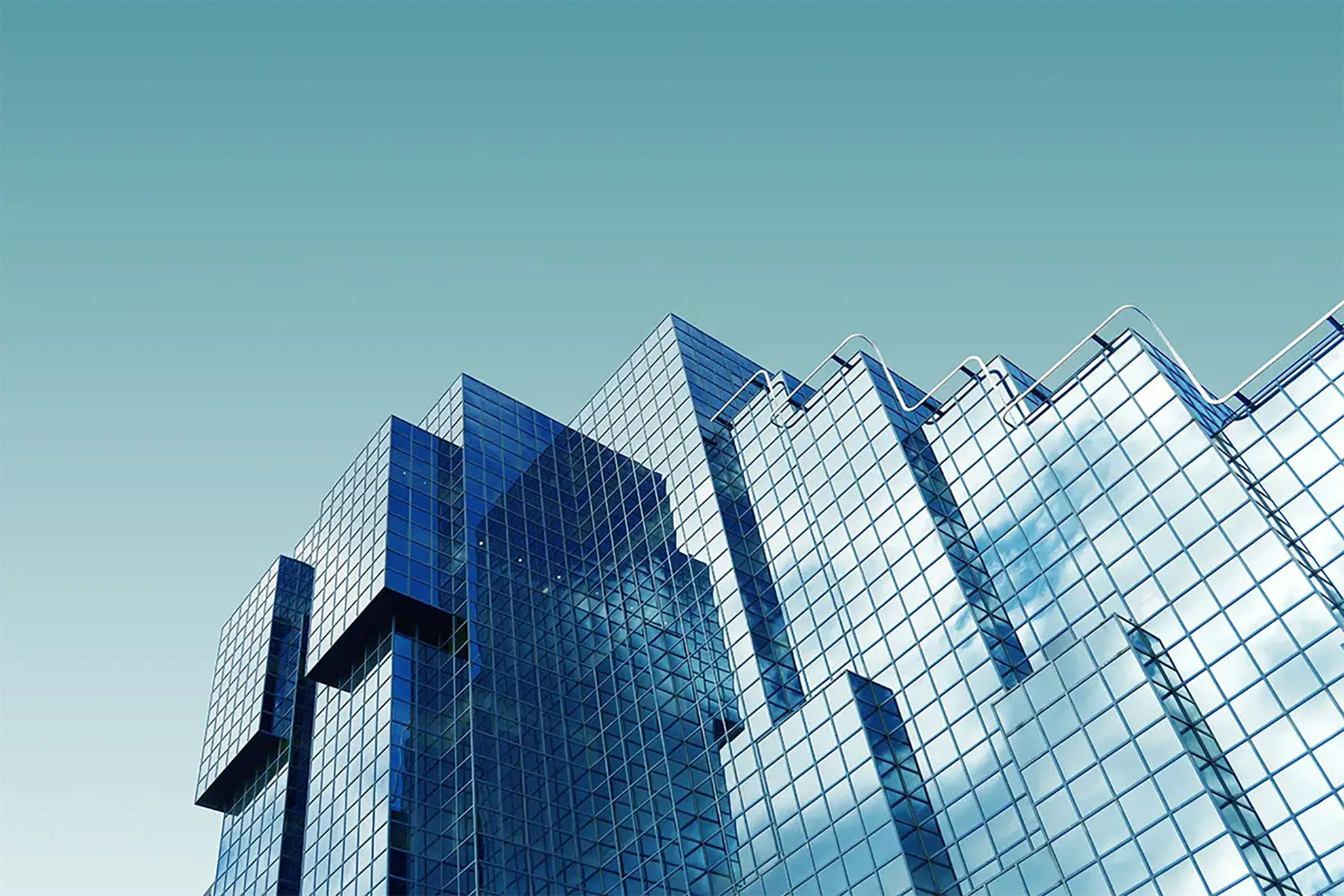 A modern skyscraper with reflective blue glass panels, featuring a unique geometric design, against a clear sky