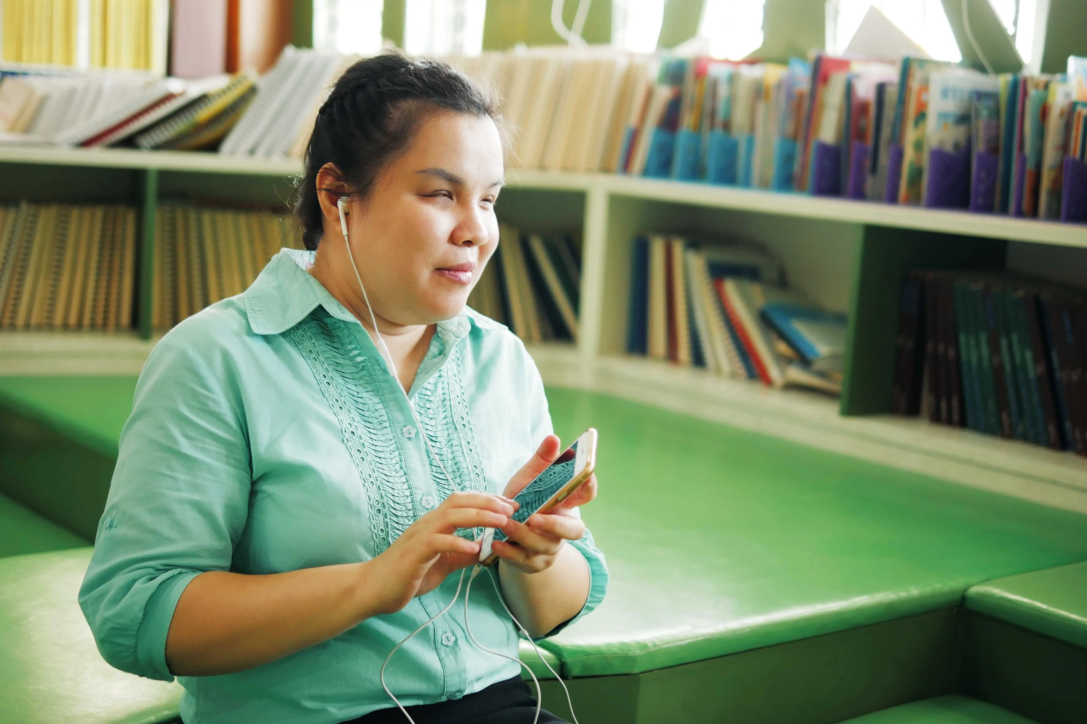 seorang wanita oku malaysia sedang mendengar sesuatu melalui telefon bimbitnya