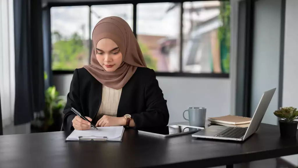 Seorang wanita mengisi borang pendaftaran hak milik tanah untuk melengkapkan urusan pemilikan