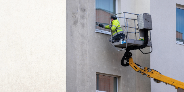 一名工人正在粉刷公寓大楼外层的墙壁