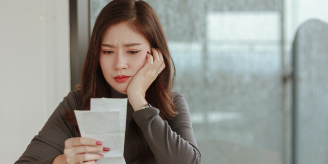 女生托腮看着账单烦恼