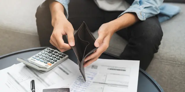 Individu meneliti bil dengan dompet kosong dan kalkulator, menggambarkan masalah kewangan serta hutang Malaysia yang semakin meningkat akibat aliran tunai tidak terkawal.