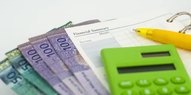 Gambar wang tunai dan kalkulator menggambarkan tekanan hutang Malaysia yang meningkat serta masalah kewangan isi rumah yang semakin serius.