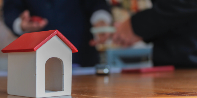 木块房子在前景，两个投资者在背景