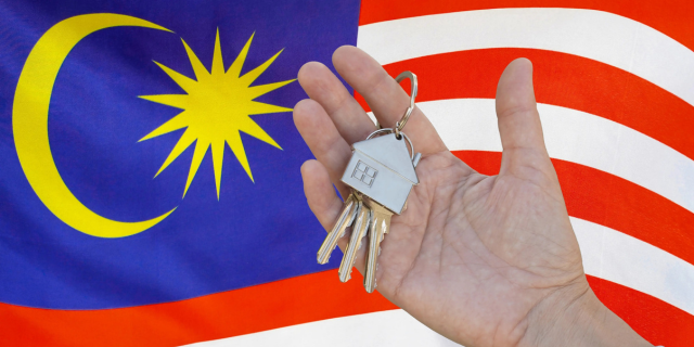 一只手握房子钥匙，背后是马来西亚国旗