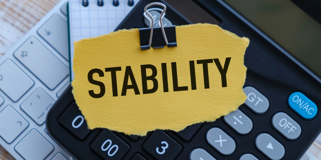 一张纸条用英语写着稳定stability,背景是计算机和平板电脑键盘